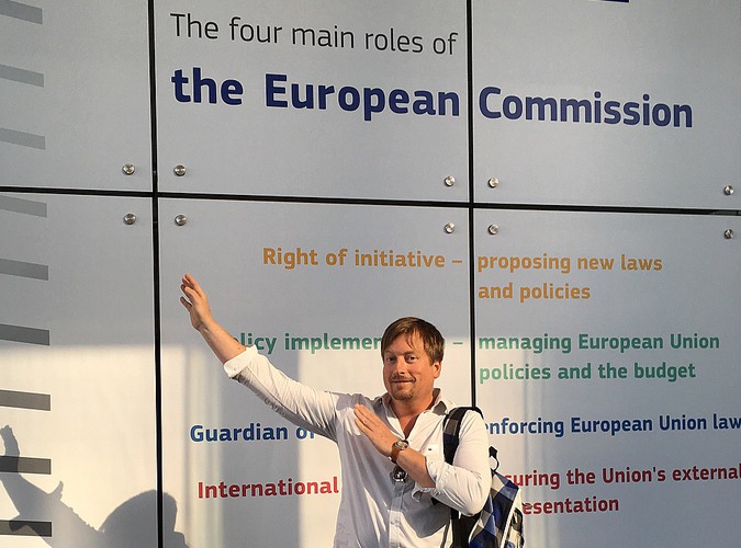 Bild på läraren Göran i Bryssel. På väggen bakom står det information om de fyra centrala rollerna för EU-komissionen